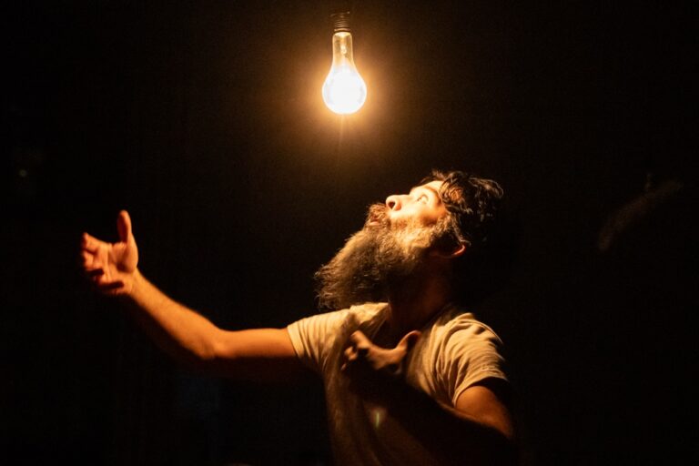 Paul Pinto sings at a light bulb